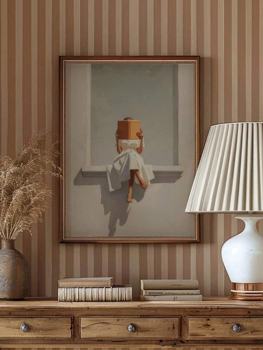 Framed neutral wall art of woman reading orange book on window ledge above vintage console