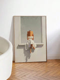 Large framed figurative print leaning on wall with woman reading on window ledge