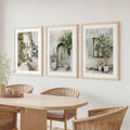 Three vertical coastal canvas prints above neutral dining table