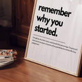 Angled motivational typography poster displayed beside books on a warm wood table