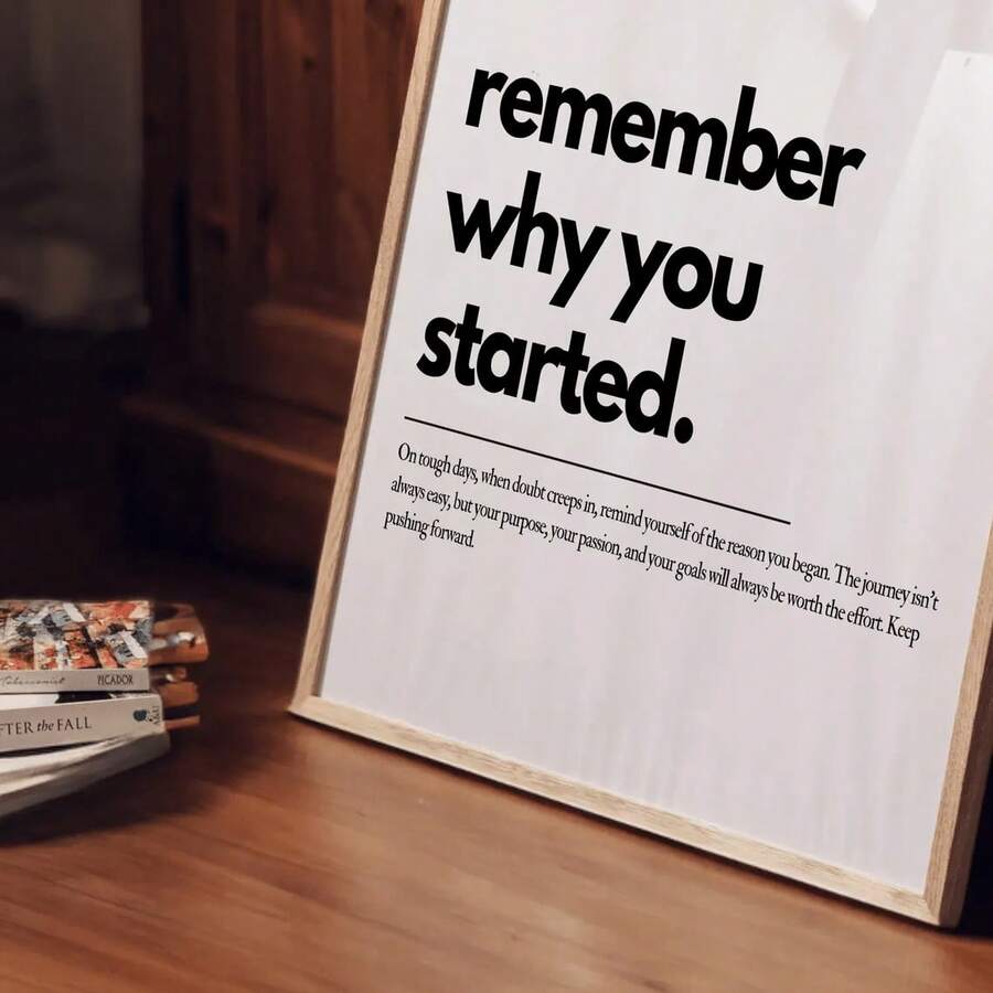Angled motivational typography poster displayed beside books on a warm wood table