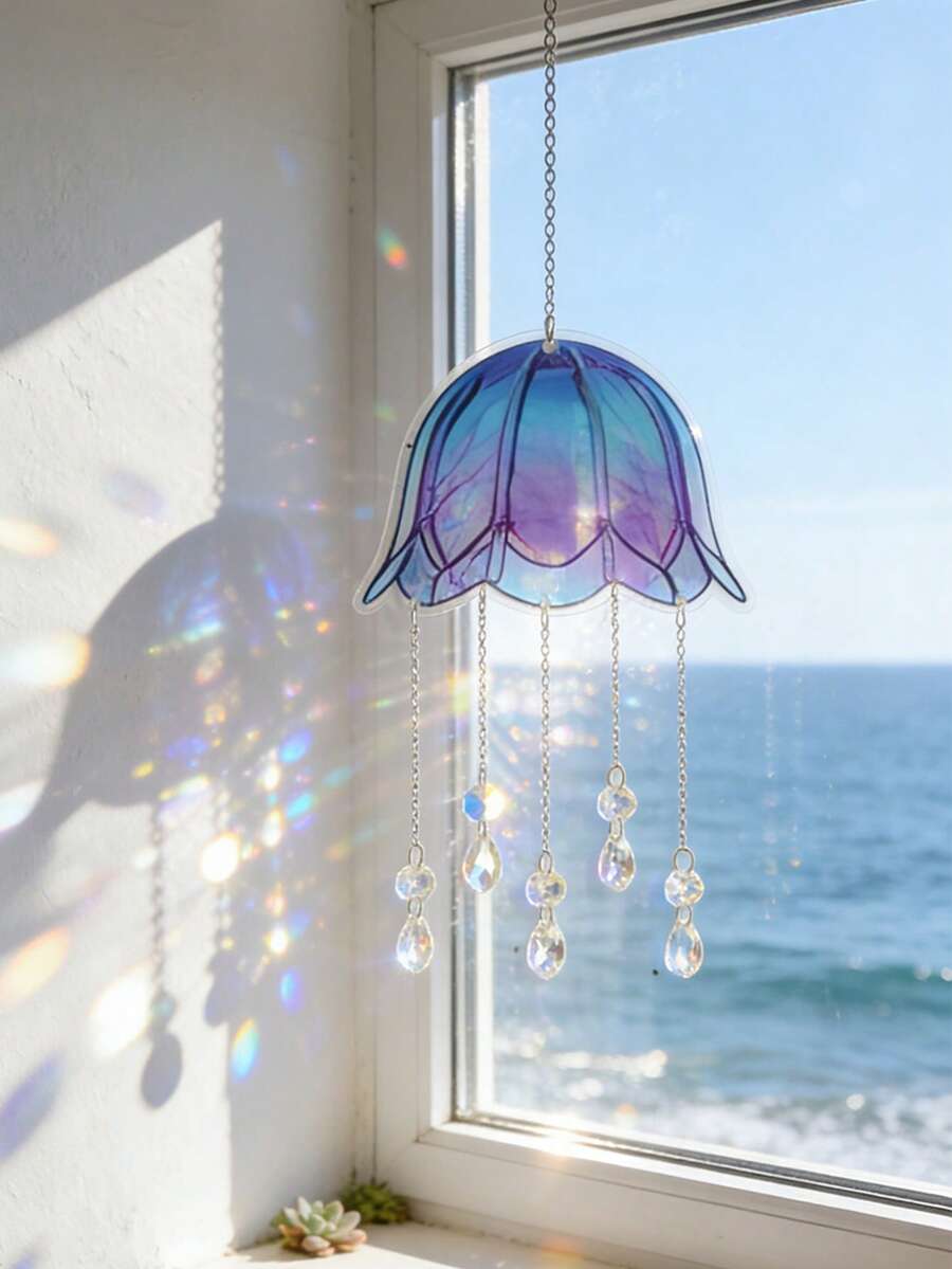 Blue-purple jellyfish acrylic suncatcher hanging in window with crystal chains and ocean view