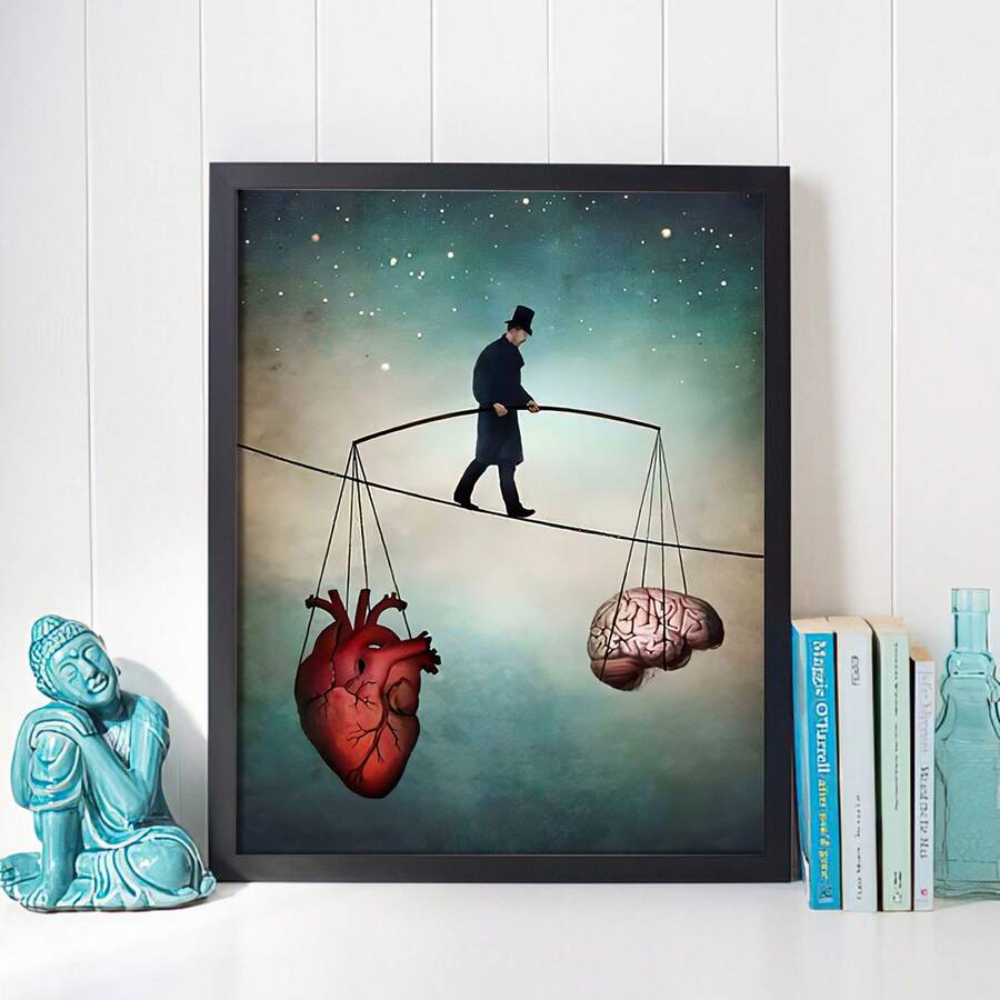 Black framed anatomical heart and brain tightrope print beside books and turquoise Buddha statue