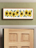 Long framed sunflower print over wood door on green wall