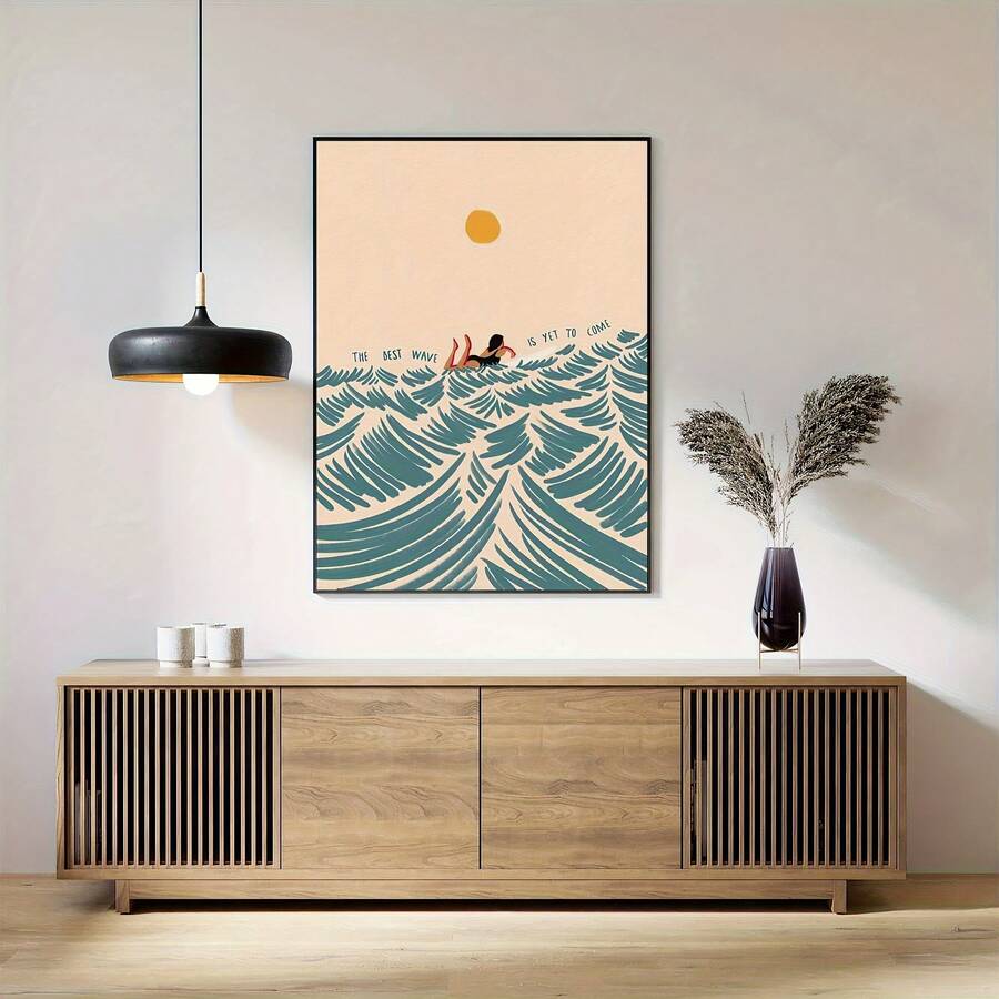 Black-framed surfing girl ocean wave poster displayed above a wooden sideboard