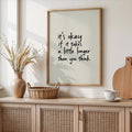 Minimalist encouragement wall art above a woven cabinet in a neutral room