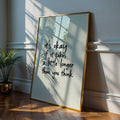Gold framed motivational quote poster with sunlight and indoor plant shadows