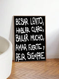 Black and white Spanish motivational quote print displayed beside a light chair