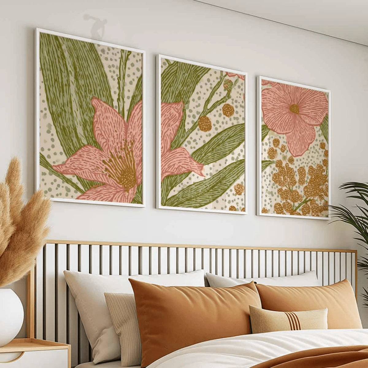 Pink floral and mustard botanical artwork in white frames above a bed with ochre pillows and a slatted headboard