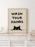 Black cat with yellow eyes peeking below hand-lettered reminder in a light wood frame
