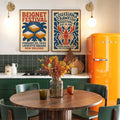 Two vintage food festival posters displayed above a kitchen dining table with green cabinets