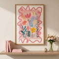 Framed pink botanical print with colorful wildflowers displayed above a console