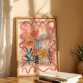 Close view of framed colorful floral illustration with coral wavy border styled on a table