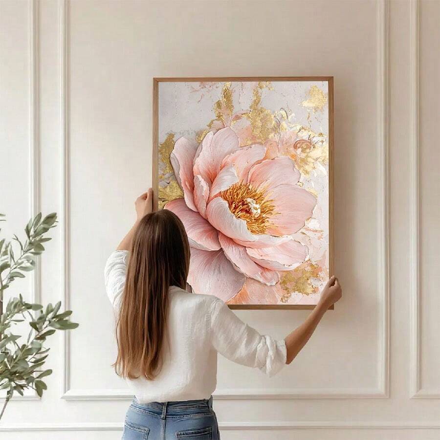 Woman positioning a large pink peony canvas on a white paneled wall