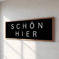 SCHÖN HIER poster with black background white lettering and wood frame