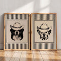 Close view of two framed dog portraits wearing cowboy hats on floor