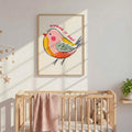 Pastel funny bird poster framed above a nursery crib