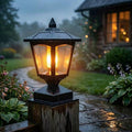 Solar post cap lantern glowing warm amber on outdoor fence post.