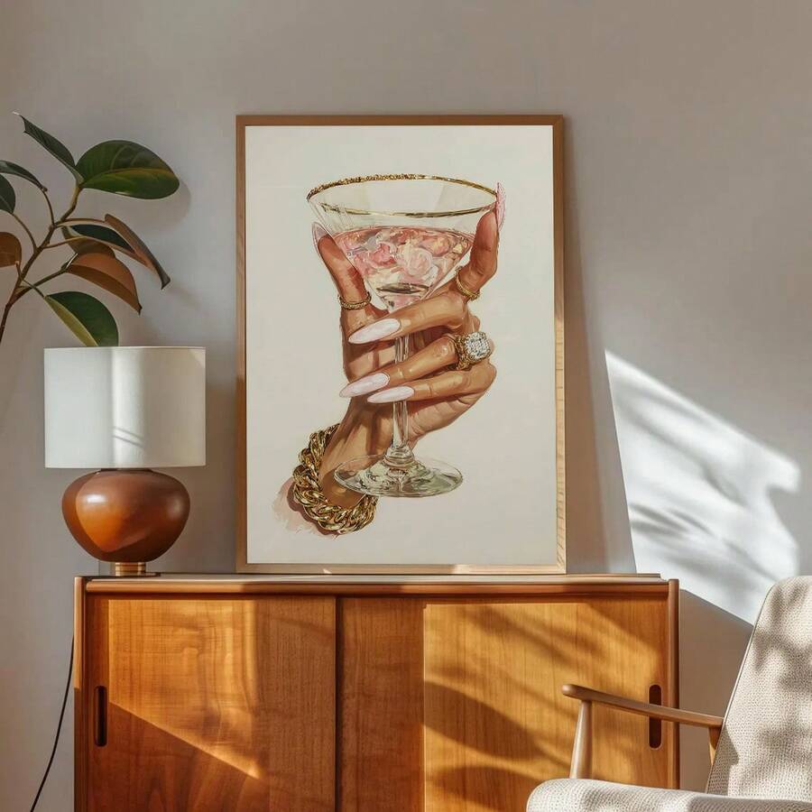 Gold-framed martini hand fashion artwork above a walnut credenza with lamp and plant