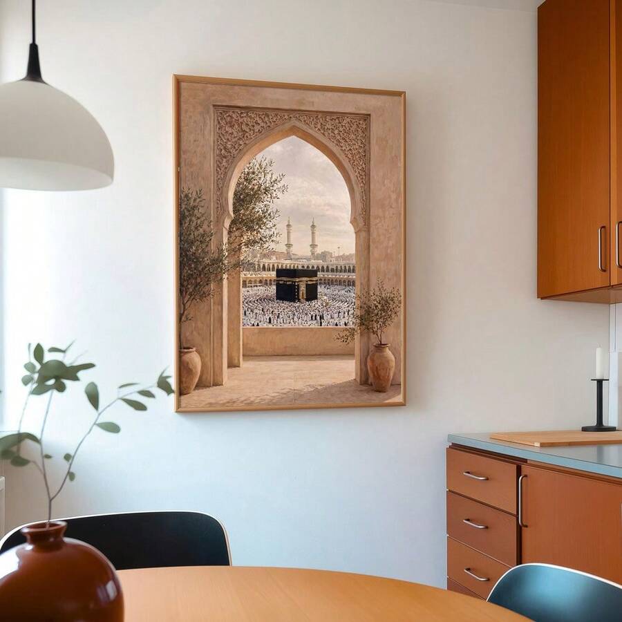 Warm framed Kaaba artwork with worshippers and twin minarets viewed through an ornate arch between potted trees