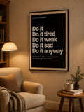 Black consistency quote poster mounted above armchair and side table in warm reading corner