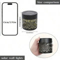 Black solar wall light fixture with top panel and circular mandala glow.