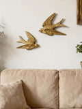 Close-up of glossy gold bird decor with dark recessed grooves and textured feathers.