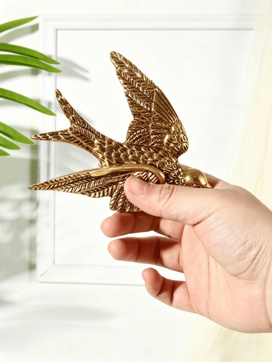 Gold bird wall accent styled near sofa, mirror, flowers, and plants.