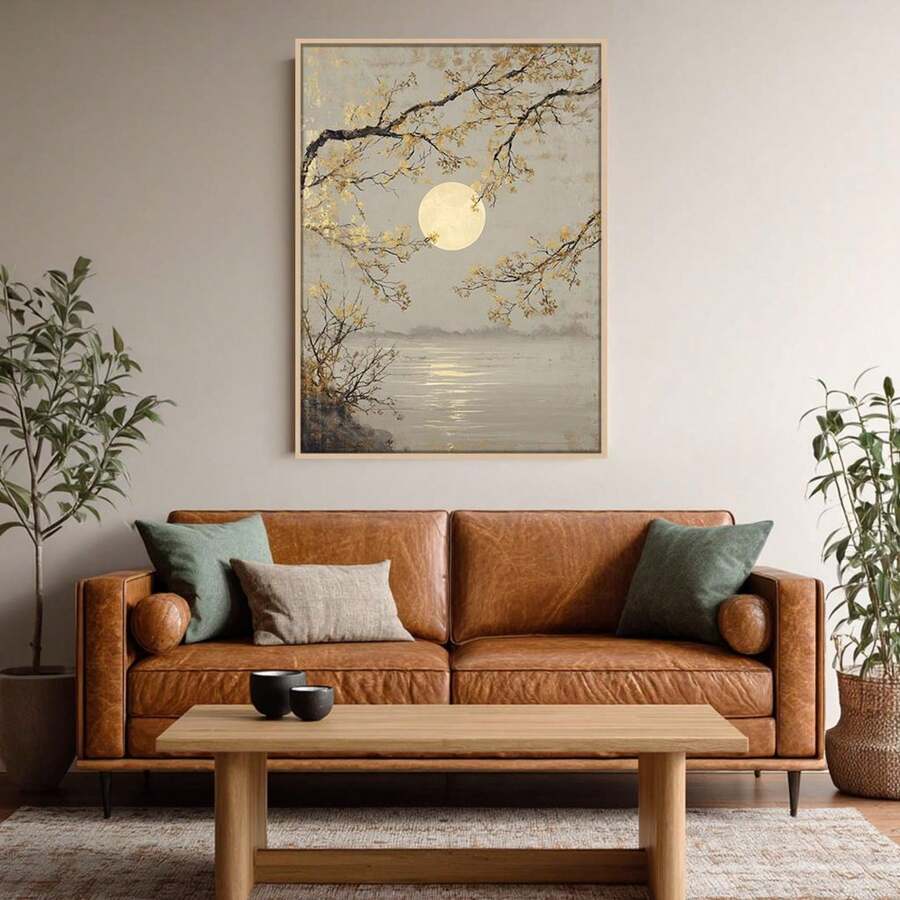 Light framed full moon landscape print above brown leather sofa in neutral living room with plants
