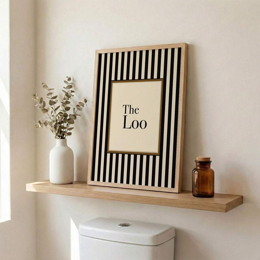 Striped The Loo print leaning on shelf above toilet with vase and amber bottle