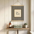 Hanging poster style The Loo print above shelf with soap bottle towels and plant
