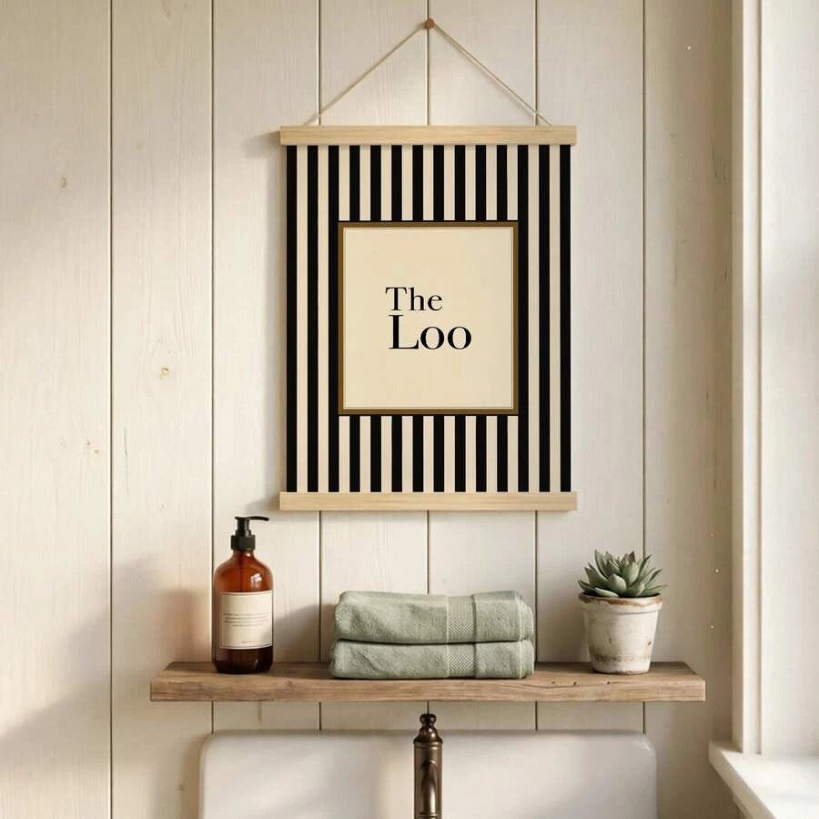 Hanging poster style The Loo print above shelf with soap bottle towels and plant