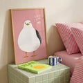 Framed funny bird wall art leaning on shelf in soft pastel room