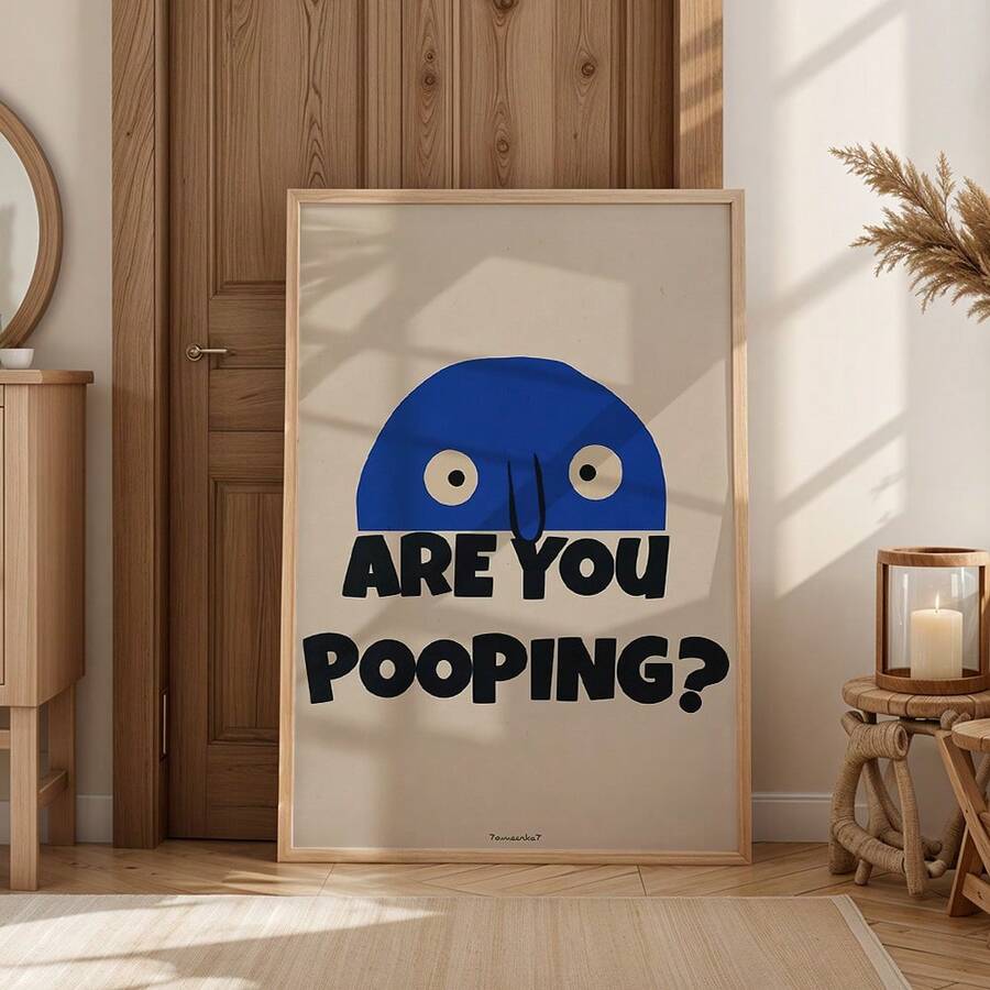 Wood framed blue face poop joke poster leaning near timber door in warm natural interior