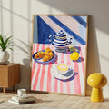 Large framed breakfast print leaning in sunny room with plant and yellow stool