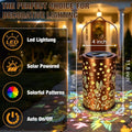 Outdoor solar lantern glowing among flowers with multicolor projected patterns.
