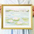 room mockup view of Framed pastel wall art print showing an abstract lily pond with water lilies, lily pads, pale blue, mint green, blush pink and gold frame styling.