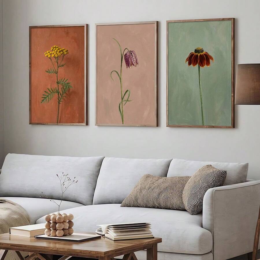 Three framed botanical flower prints above dining table with natural wood chairs