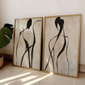Close view pair framed black line figure artworks leaning against wall with monstera plant