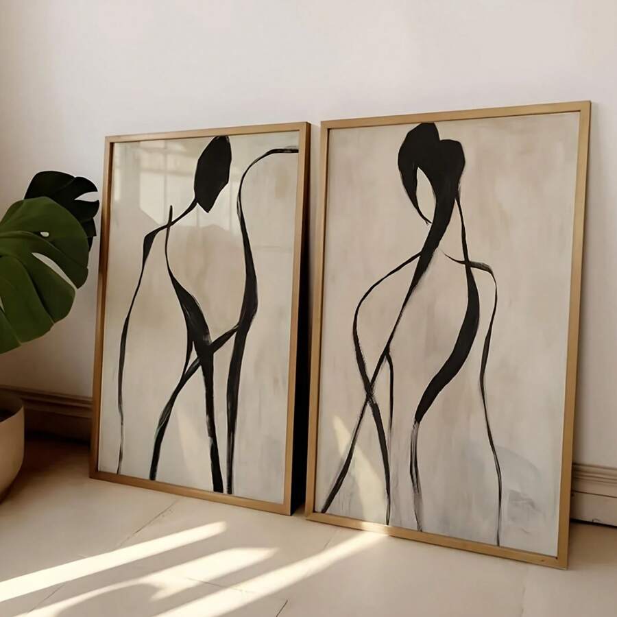 Close view pair framed black line figure artworks leaning against wall with monstera plant