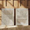 Framed pair of taupe relief-style prints against warm wood paneling