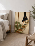 Framed literary woman print leaning beside bed in neutral bedroom