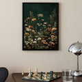 Black framed dark green floral wall art above desk with chess board and chrome lamp