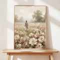 Framed impressionist floral meadow print on wood table with robed figure among roses