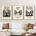 Three vintage style motivational framed posters above white sofa with black and cream city illustrations