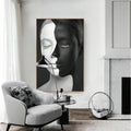 Large split-face woman portrait wall art displayed beside a fireplace and armchair