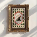 close-up artwork detail of Whimsical woodland canvas wall art showing a cute skunk holding a red flower with golden star, floral vines and vintage harlequin pattern.