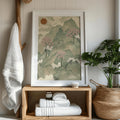 Japanese landscape print in a white frame beside wood shelving and greenery