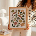 canvas option view of Framed botanical wall art showing illustrated tree leaves as a labeled species guide with cream background, olive greens and vintage nature chart styling.