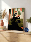 Woman with a cocktail beside a black cat and green sofa in a wood-framed portrait print above a dresser